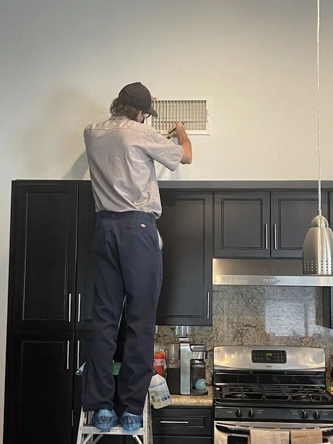 Technician inspecting an air vent during HVAC service in Butler